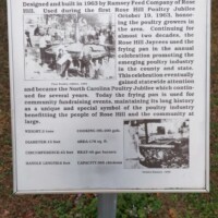 Informational sign titled 'World’s Largest Frying Pan' with text and two black-and-white photos detailing the pan’s creation, size, and use in North Carolina poultry festivals.