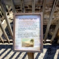 Wooden interpretive sign titled 'Who Built the Eagle Nest?' explaining the Civilian Conservation Corps' 1930s construction of the Eagle Nest scenic overlook, set against a wooden fence with a small black-and-white image of CCC workers at the bottom.