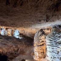 Visitors observing massive cave formations inside Fantastic Caverns in Springfield, Missouri, where stalactites and stalagmites merge into towering mineral columns.