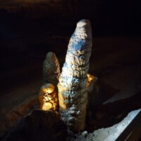 Tall stalagmite formation inside Fantastic Caverns in Springfield, Missouri, highlighted by cave lighting to reveal mineral textures and surrounding flowstone.