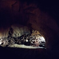Dimly lit cave interior at Fantastic Caverns in Springfield, Missouri, with rocky ground and illuminated mineral formations creating dramatic light and shadow.