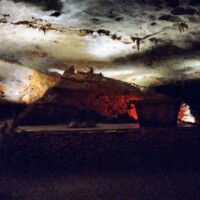 Red and white illuminated cave formations inside Fantastic Caverns in Springfield, Missouri, with rugged rock surfaces and a stone trough in the foreground.