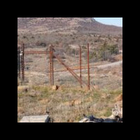 A wooden fence stretching across a hilly landscape, with rolling green terrain visible in the background.