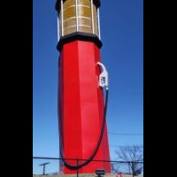 Person standing next to World's Tallest Gas Pump in Sapulpa Oklahoma showing massive scale of 66-foot roadside attraction