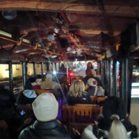 Inside the trolley during the Ghosts and Gravestones tour St Augustine, with passengers seated and the tour guide speaking up front under string lights