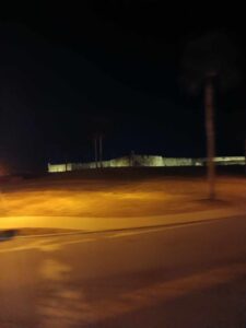 Stone fort illuminated at night during the Ghosts and Gravestones tour St Augustine, with palm trees silhouetted against the sky.