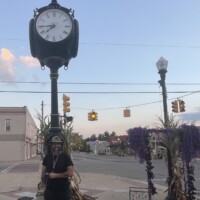 Downtown Holly Michigan street clock surrounded by fall decorations, with cornstalks and purple fabric under a clear evening sky