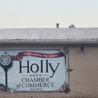Holly Michigan Chamber of Commerce mural celebrating 150 years, with vintage-style street clock and decorative ribbon on brick building
