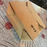 Closed brown paper takeout box labeled ‘#53’ on retro-style table at The Laundry Restaurant in Fenton Michigan