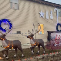 Illuminated reindeer and sleigh decorations outside Christmas Winter Wonderland in Fort Smith, Arkansas, photographed at dusk with wreaths, stars, and candy-cane lights on the building.