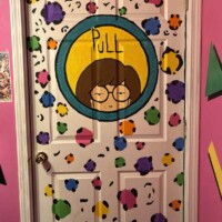 Colorful cartoon-style bathroom door artwork inside Flashback Pizza and Milkshakes in Rogers, Arkansas, featuring playful retro illustrations and bright paint splatter details.