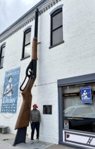 World's largest BB gun towering outside Daisy Airgun Museum building with Zach in Rogers, Arkansas