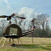 Hay bale helicopter sculpture with mirror and rotor blades at Jim Bird's Hay Bale Art in Forkland Alabama