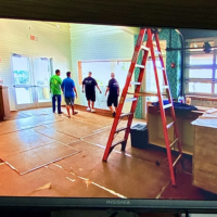 Screenshot from Tanked Season 7 Episode 6 showing the ATM crew inside Salt Life Food Shack during the aquarium installation with the tank footprint marked out on the floor in St. Augustine Beach Florida