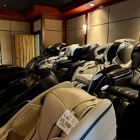 Rows of black and white massage chairs lined up inside the Man Cave at Furnitureland South, with price tags showing costs starting around $3,100