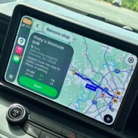 A vehicle's CarPlay touchscreen display showing navigation directions to Pinky's Westside Grill at 1600 W Morehead Street in Charlotte, NC. The screen shows an estimated arrival time of 11:44, a 31 minute drive covering 15 miles, with a note that the route is the fastest due to current traffic conditions and that plenty of parking is available. A blue route line traces the path on the map. The vehicle's dashboard controls and volume knob are visible at the bottom of the frame.