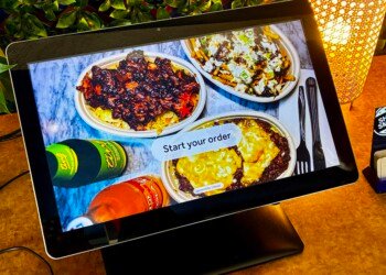 Self-service ordering tablet inside Carib Shack displaying photographs of the restaurant’s food.