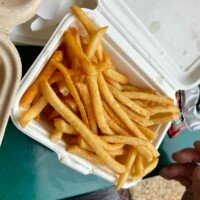 Golden french fries served in an open takeout container at Carib Shack.
