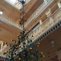 Ornate multi-story atrium inside the Anheuser-Busch Brew House with a large wrought-iron chandelier hanging from the skylight.