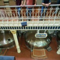 Large copper brew kettles inside the Anheuser-Busch Brew House, viewed from an upper walkway with visitors looking down.