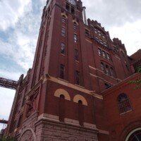 The historic 1891 clock tower of the Anheuser-Busch brewery building against a cloudy sky.
