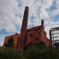 A tall brick smokestack rising from the Anheuser-Busch brewery power plant building.