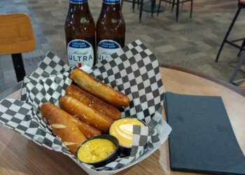 A basket of soft pretzel bites with beer cheese and mustard dip, next to two bottles of Michelob Ultra at the Anheuser-Busch tasting area.