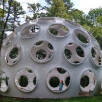 Full exterior view of Buckminster Fuller's Fly's Eye Dome at Crystal Bridges Museum, with Nancy standing inside one of the circular openings.