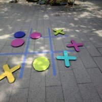 Giant human-scale tic-tac-toe game painted on the courtyard pavement at Crystal Bridges Museum.