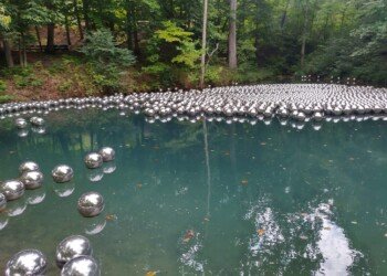 Hundreds of mirrored stainless steel spheres from Yayoi Kusama's Narcissus Garden floating on Crystal Pond at Crystal Bridges Museum.