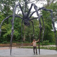 Zach standing beneath Louise Bourgeois's giant bronze spider sculpture Maman at Crystal Bridges Museum in Bentonville, Arkansas.