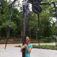 Nancy hugging one of the legs of Louise Bourgeois's giant spider sculpture Maman at Crystal Bridges Museum.