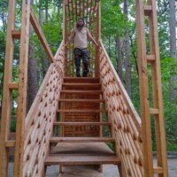 Zach standing at the top of a striking wooden lattice staircase art installation at Crystal Bridges Museum.