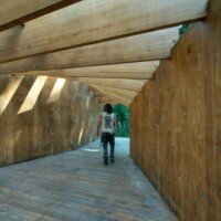 Zach walking through a curved wooden tunnel-like pavilion structure on the Crystal Bridges trail.