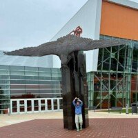 Nancy with arms raised, pretending to be attacked by the World's Largest Bronze Falcon