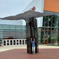 Nancy continuing the bit, still pretending to be attacked by the giant bronze falcon at Bowling Green State University