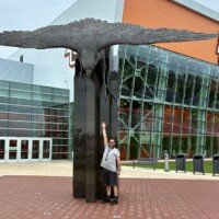 Zach standing beneath the World's Largest Bronze Falcon outside the Stroh Center in Bowling Green, Ohio