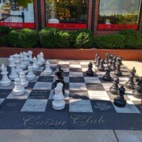Giant outdoor chessboard with black and white pieces on the Caissa Club patio outside the World Chess Hall of Fame in St. Louis