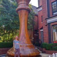 Nancy in white sunglasses standing at the base of the 20-foot mahogany World's Largest Chess Piece in St. Louis